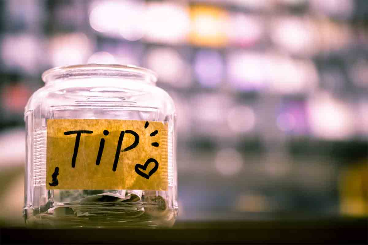 A glass bottle filled with currency notes and coins, with the word 'Tips' written on a label outside which indicates "No Withdrawal Zone" of Saving Money.